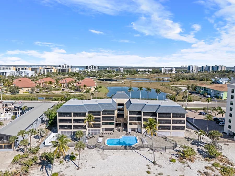 Aerial view of the beachfront resort building with an outdoor pool and palm trees